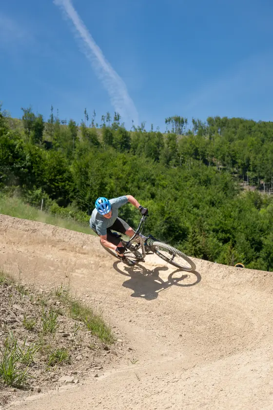 Jezdec v klopené zatáčce na modré flow trati bikeparku Opálená