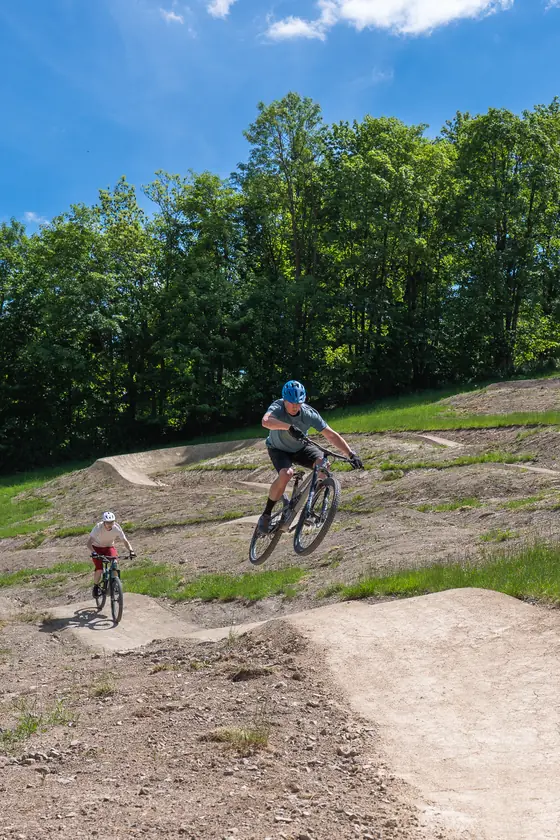 Dospělý a dítě jedou společně na pumptracku bikeparku Opálená