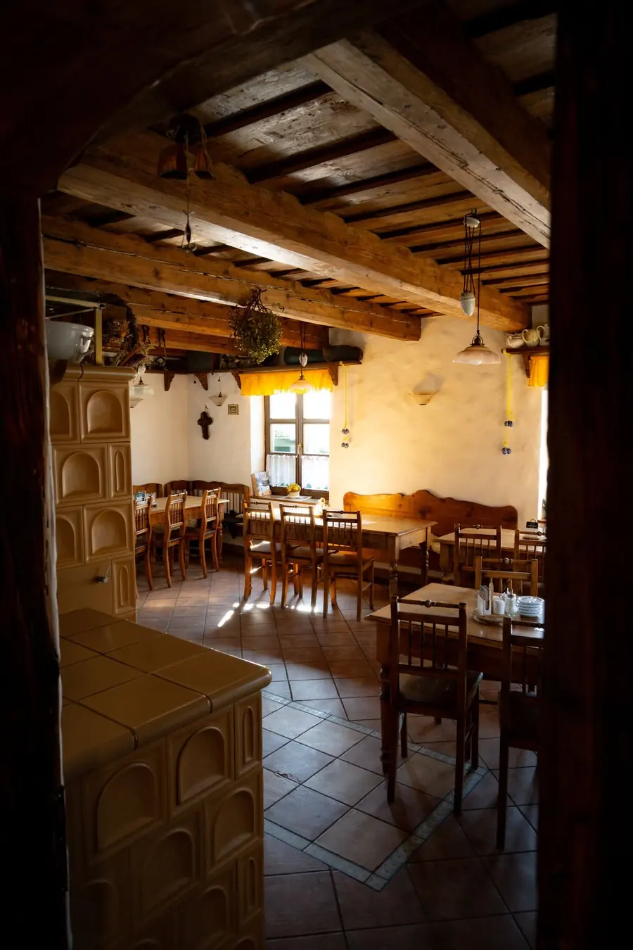 Stylový interiér restaurace Čeladná s dřevěnými trámy a kachlovými kamny